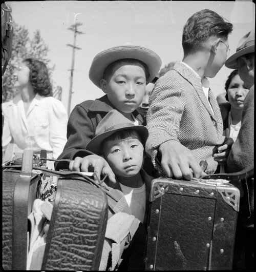 Turlock, California. These young evacuees of Japanese ancestry are awaiting their turn for baggage . . .